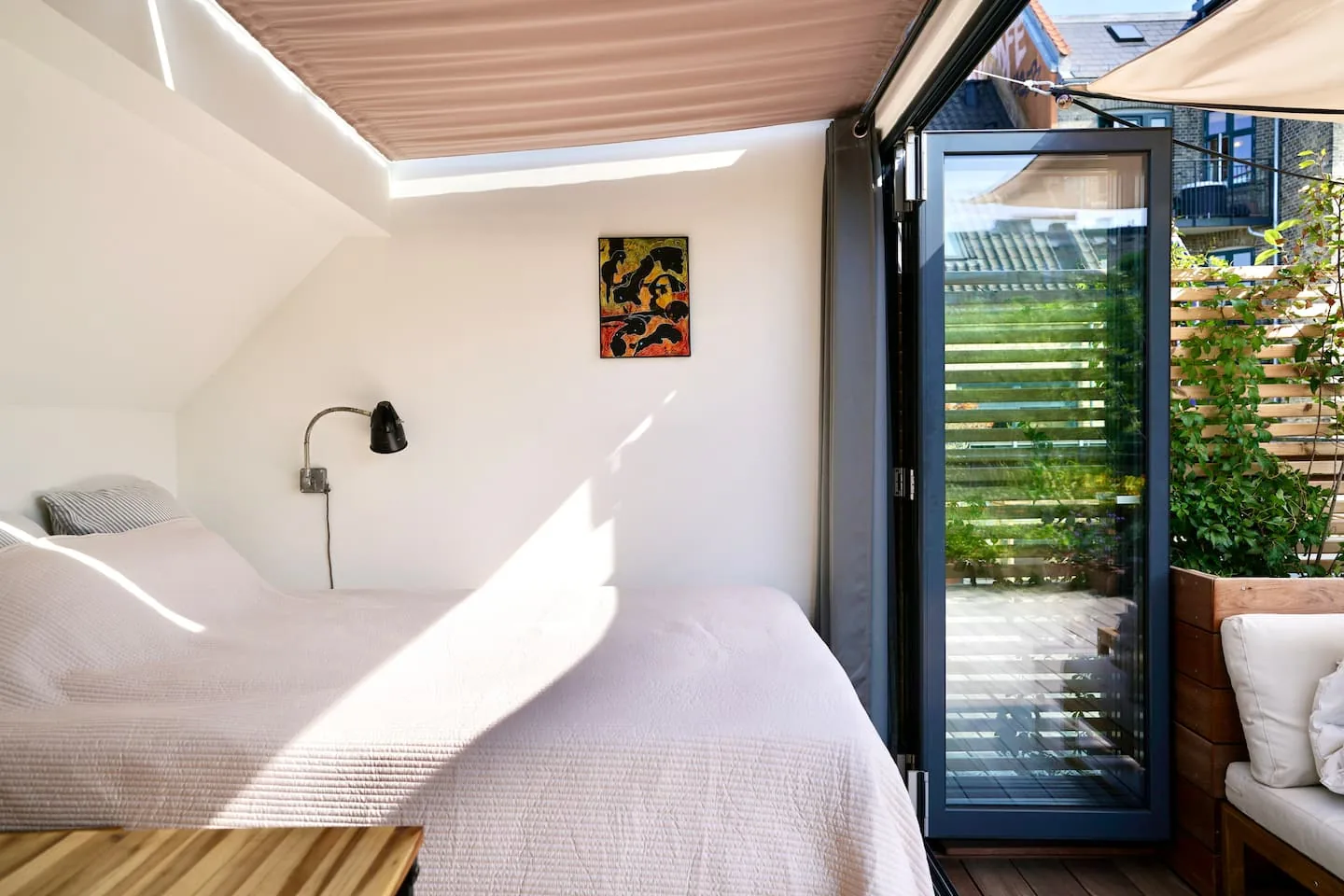 Bedroom with sloped glass roof and an open glass door to the terrace